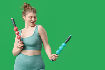 Sporty young woman with massage rollers on  green background