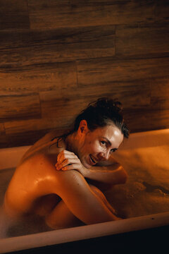 Girl lying in the bathtub by candlelight