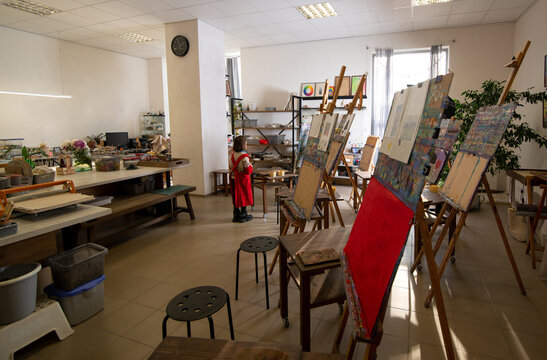 Little child in apron in large classroom-workshop in art school
