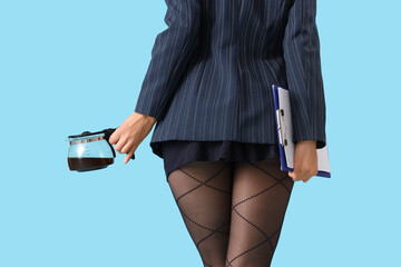 Attractive secretary with coffee pot and clipboard on blue background, back view