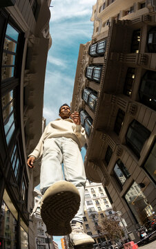 Fisheye. Full body. Man walking in city street in sunlight from below