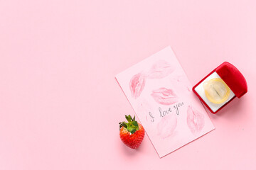 Fresh strawberry, card and engagement box with condom on pink background. Sex education