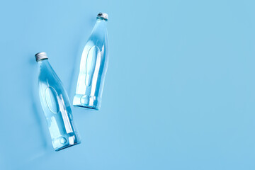 Glass bottles of clean water on blue background