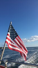american flag on back of a boat in the water on a sunny summer day © Olivia