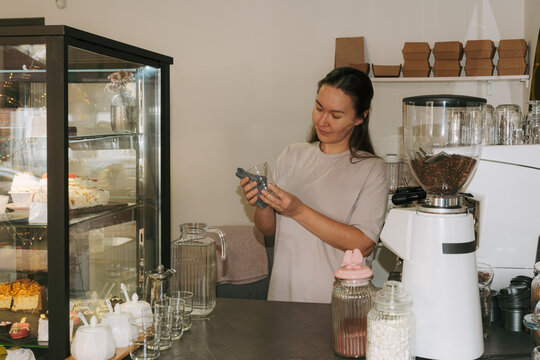 Owner preparing drinks in a cozy cafe during afternoon hours