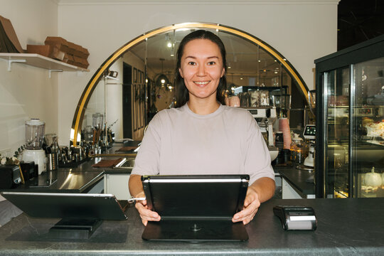 Owner of a cozy cafe assisting customers at the counter