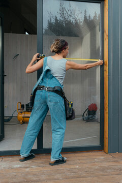 Woman builder measuring for construction repairs in outdoor setting