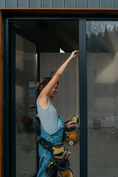 Woman builder measuring window during construction in modern home