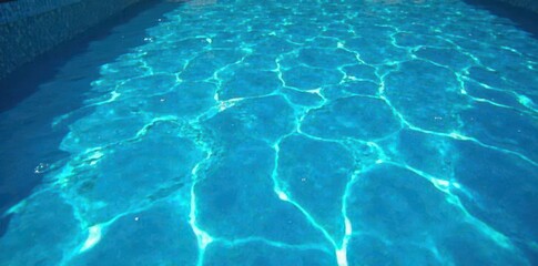 Deep blue swimming pool water, strong surface disruption, visible texture, pattern, motion