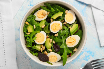 Bowl with healthy salad with quail eggs and arugula on blue grunge background, closeup