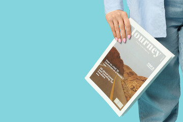 Beautiful young woman with magazine on blue background, closeup