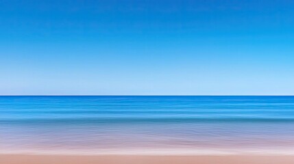 Obraz premium Waterscape abstract background idea. Serene coastal view with clear blue sky and calm ocean waves on sandy beach.