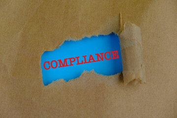 COMPLIANCE appearing behind torn a Blue paper.