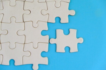 Obraz premium Frame of white puzzle elements on blue background. Business or educational concept. Selective focus, copy space