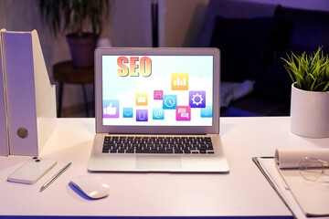 Laptop with abbreviation SEO on desk in dark office