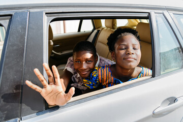 Smiling sibling waving hand from car while back to school