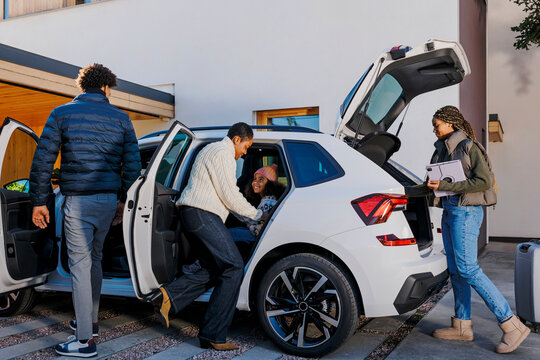 Family packing car for road trip, loading luggage and bags