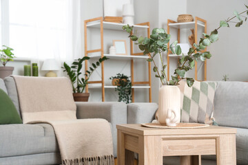 Vase with eucalyptus branches on table in living room
