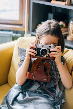Young girl captures memories with camera in cozy interior setting