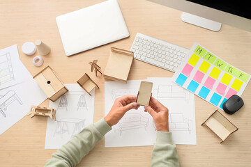 Male furniture designer with miniature models working on table, top view
