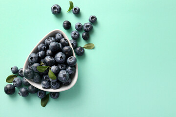 Bowl with ripe blueberry on turquoise background