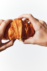 Hands holding a croissant on a white background, close up shot