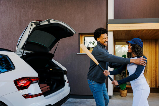 Father congratulating daughter after baseball practice next to car