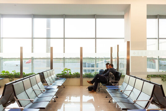Two travelers sit in a bright airport 