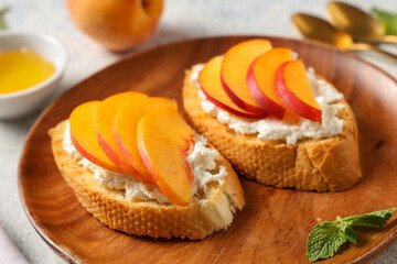 Wooden plate of peach bruschetta with ricotta and mint on white background, closeup