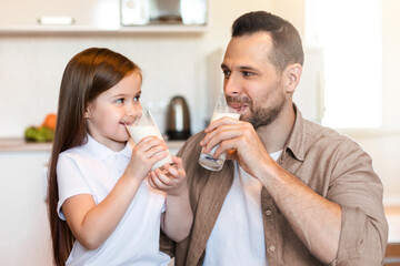 Breakfast With Dad. Father And Little Daughter Drinking Milk Sitting In Kitchen At Home