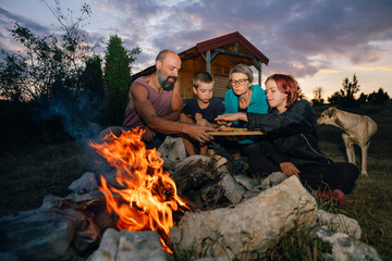 Family with a dog Eating by a Campfire