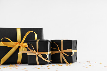 Black gift boxes and confetti on grey background