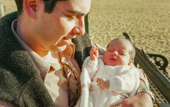 Analog film of young father with newborn baby in her arms.