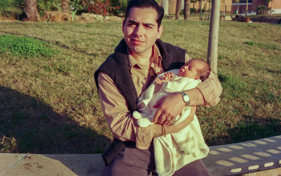 Analog film of young father with newborn baby in her arms.