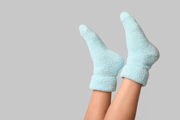 Legs of young woman in warm blue socks on grey background