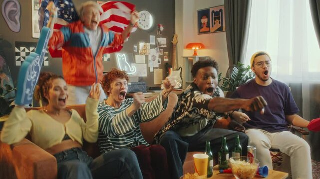 Group of ecstatic friends cheering and celebrating goal with USA flag and foam fingers, sitting on couch and watching soccer game on TV, with snacks and drinks nearby in stylish living room