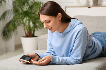 Young woman with diabetes measuring blood sugar level at home