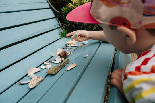 Boy Exploring Beach Finds on a Painted Bench