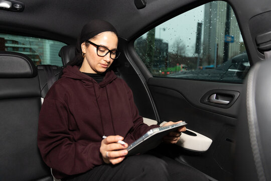 Student in niqab using tablet in car while studying