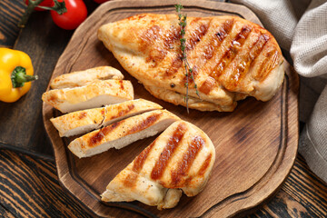Board with tasty grilled chicken breast and thyme on wooden background