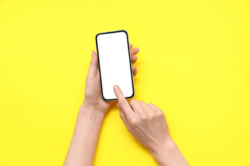 Female hands with mobile phone on yellow background