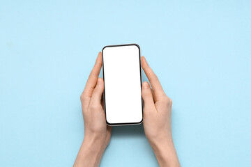 Female hand with mobile phone on blue background