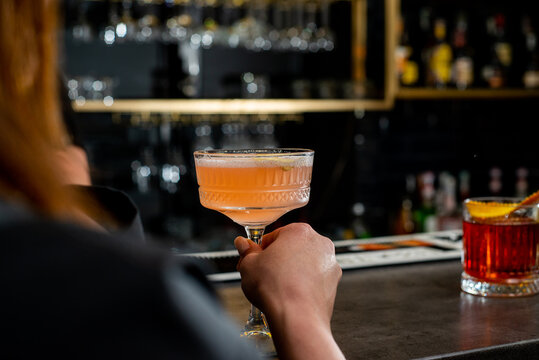 Faceless young woman holding an orange cocktail
