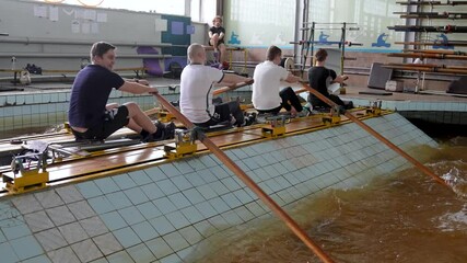 Rearview rowing male team works with paddles in pool simulator while coach observes. Sportsmen team focus on technique coordination and preparing for upcoming competitions, hobby and exercising - Powered by Adobe