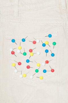 Denim jeans and colourful paper pins on the pocket and flash