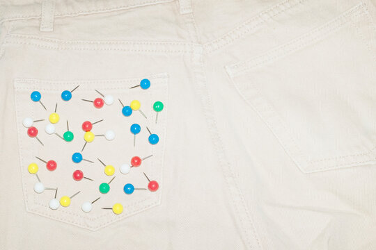 Denim jeans and colourful paper pins on the pocket and flash