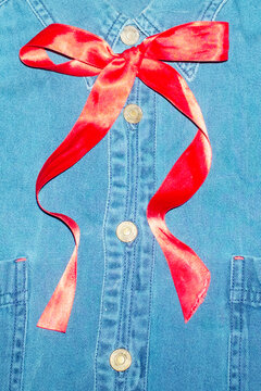Person wearing formal denim shirt with cute red silk ribbon bow 
