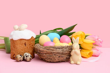 Sweet Easter cake with eggs, toy rabbit and beautiful tulip flowers on pink background