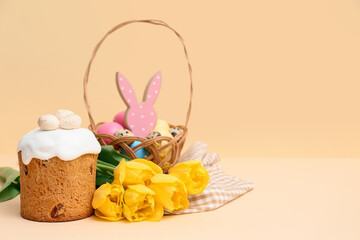 Wicker basket with eggs, sweet Easter cake and beautiful tulip flowers on yellow background