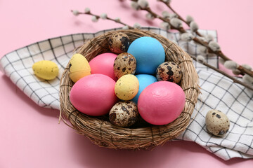 Nest with Easter eggs and pussy willow branches on pink background, closeup